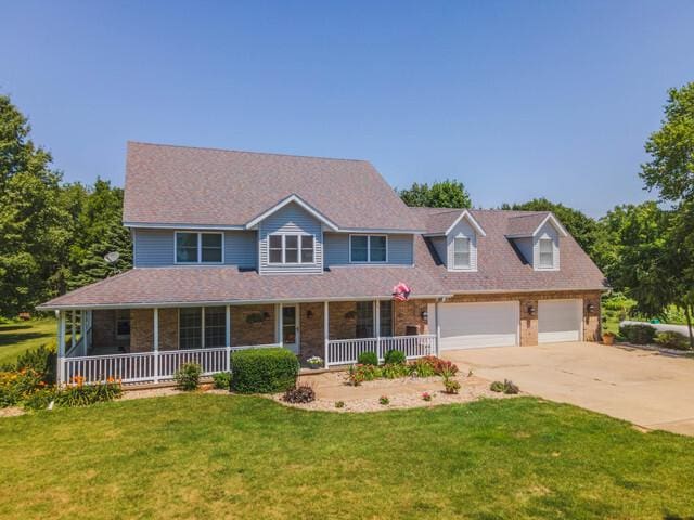 13494 E 75 N Rd, Heyworth, IL 61745 - colonial-style house featuring covered porch, concrete driveway, a front lawn, and a garage