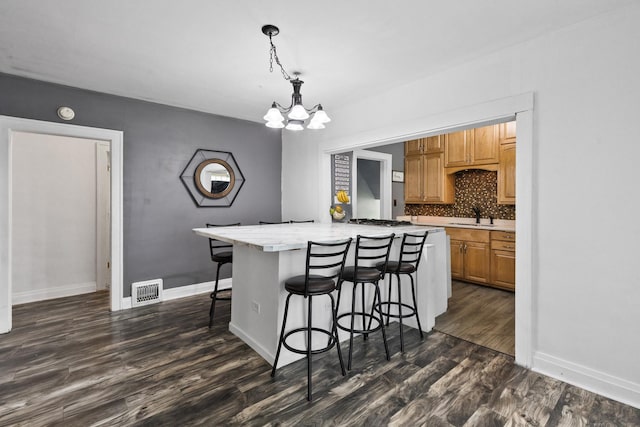 956 S Elm Ave, Kankakee, IL 60901 - kitchen with a chandelier, light countertops, dark wood-style floors, a center island, and a kitchen bar