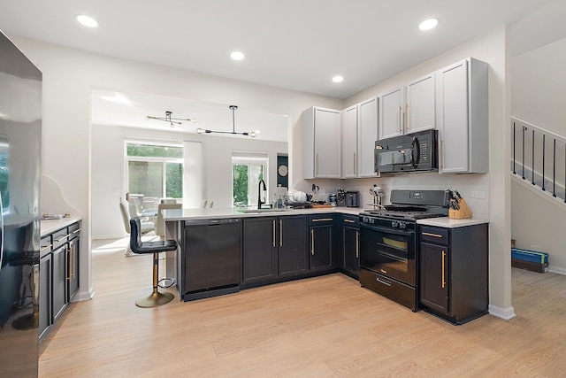 1528 Peachtree Ln, Lockport, IL 60441 - kitchen with black appliances, light wood-type flooring, a peninsula, light countertops, and a kitchen breakfast bar
