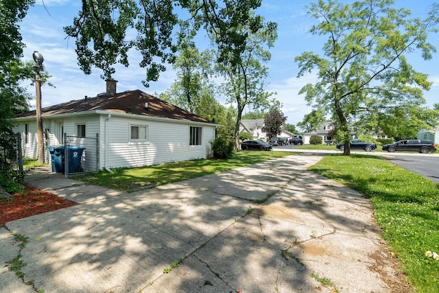930 S Chatham Ave, Addison, IL 60101 - view of home's exterior featuring concrete driveway, a lawn, and a chimney