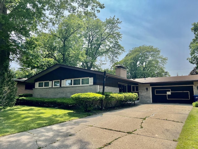 336 Flossmoor Ave, Waukegan, IL 60085 - ranch-style house with concrete driveway, a chimney, a front lawn, an attached garage, and brick siding
