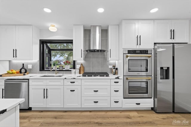111 Mayberry Ct, Rolling Meadows, IL 60008 - kitchen featuring stainless steel appliances, wall chimney range hood, white cabinetry, light wood finished floors, and decorative backsplash