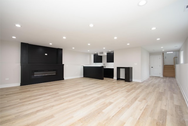 8402 S Carpenter St, Chicago, IL 60620 - unfurnished living room with light wood-style floors, bar with sink, stairs, recessed lighting, and a large fireplace