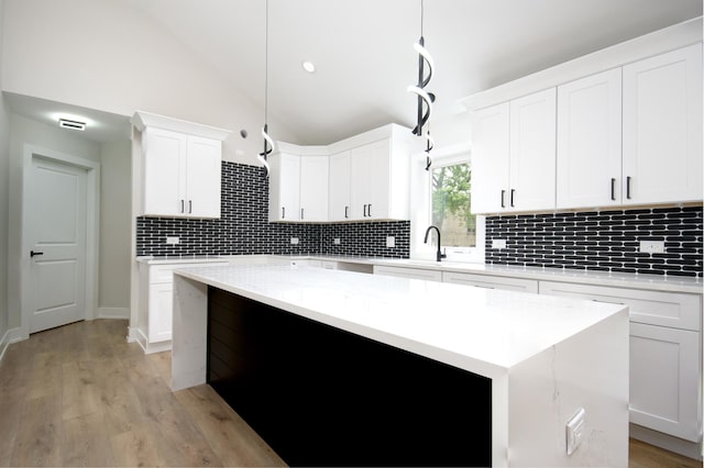 8402 S Carpenter St, Chicago, IL 60620 - kitchen with lofted ceiling, a center island, decorative backsplash, white cabinetry, and light wood-style floors