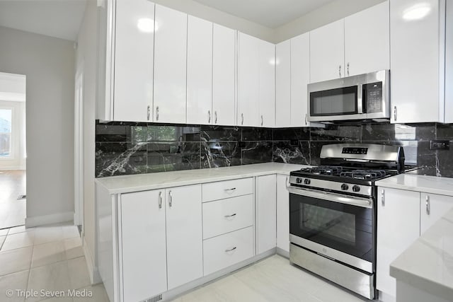 3425 W Carroll Ave, Chicago, IL 60624 - kitchen with appliances with stainless steel finishes, backsplash, white cabinetry, light stone countertops, and light tile patterned floors