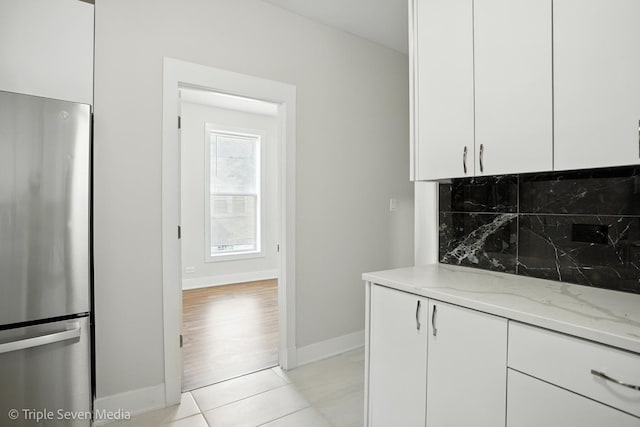 3425 W Carroll Ave, Chicago, IL 60624 - kitchen with freestanding refrigerator, light stone counters, decorative backsplash, white cabinets, and light tile patterned flooring