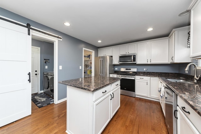 741 Oakwood St, Minooka, IL 60447 - kitchen featuring appliances with stainless steel finishes, wood finished floors, independent washer and dryer, white cabinets, and a kitchen island