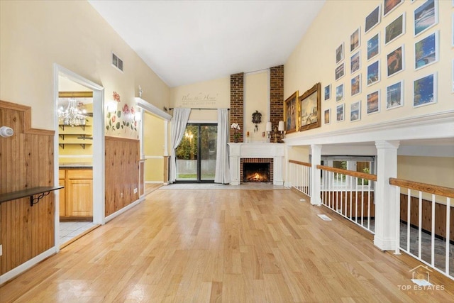 1018 Bob O Link Ln, Darien, IL 60561 - unfurnished living room with light wood finished floors, high vaulted ceiling, a brick fireplace, and a wainscoted wall