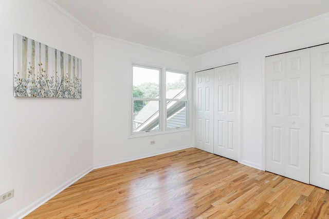 902 Heathrow Ln, Naperville, IL 60540 - unfurnished bedroom featuring two closets, light wood-style floors, and ornamental molding