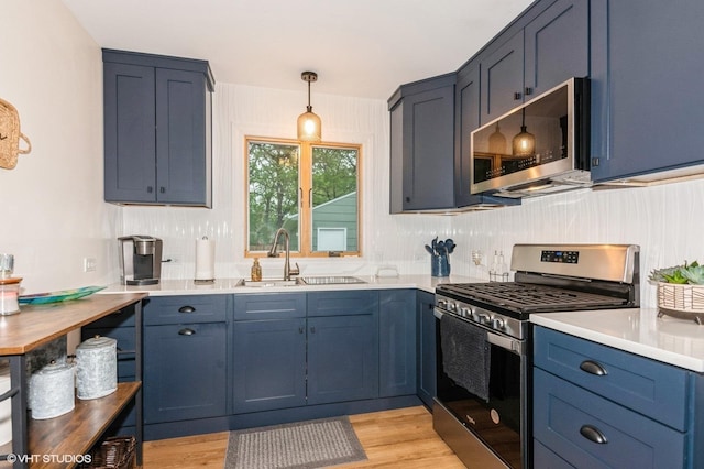 2365 N Barrington Woods Rd, Palatine, IL 60074 - kitchen featuring stainless steel appliances, light wood-type flooring, light countertops, hanging light fixtures, and blue cabinets