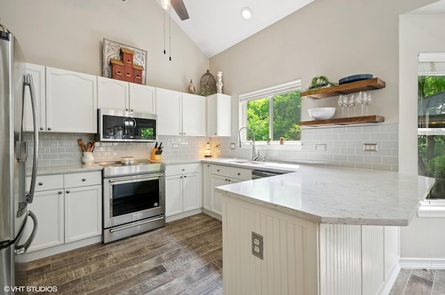 2570 Fairfax Ln, Lake In The Hills, IL 60156 - kitchen with appliances with stainless steel finishes, a peninsula, dark wood-style floors, white cabinetry, and high vaulted ceiling