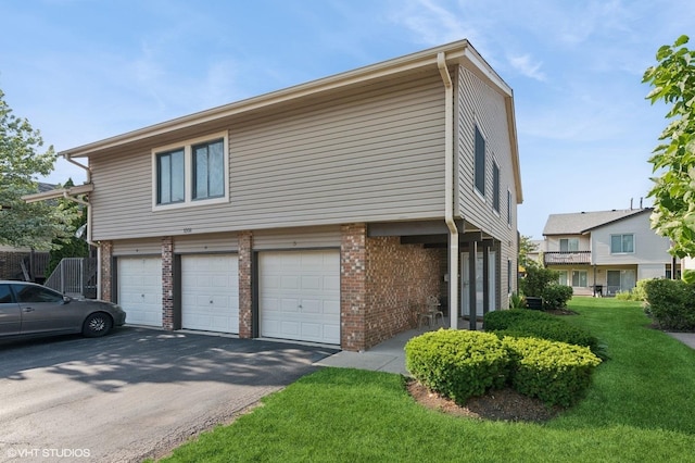 1351 Kingsbury Dr Unit 5, Hanover Park, IL 60133 - view of side of home with asphalt driveway, a lawn, brick siding, and a garage