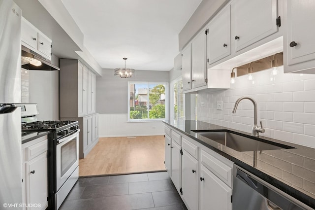 1351 Kingsbury Dr Unit 5, Hanover Park, IL 60133 - kitchen featuring appliances with stainless steel finishes, under cabinet range hood, white cabinets, backsplash, and a chandelier