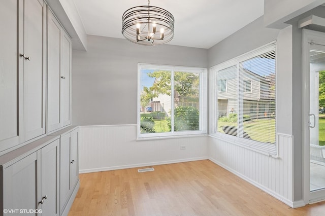 1351 Kingsbury Dr Unit 5, Hanover Park, IL 60133 - unfurnished dining area featuring wainscoting, light wood finished floors, and a chandelier