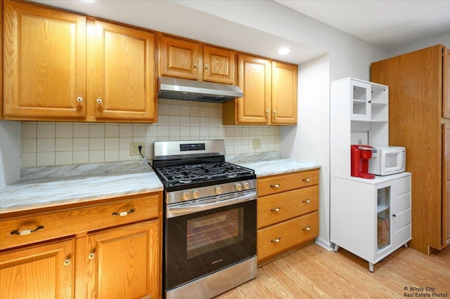 36 W Green Meadows Blvd, Streamwood, IL 60107 - kitchen with stainless steel range with gas stovetop, under cabinet range hood, white microwave, light wood-style floors, and backsplash