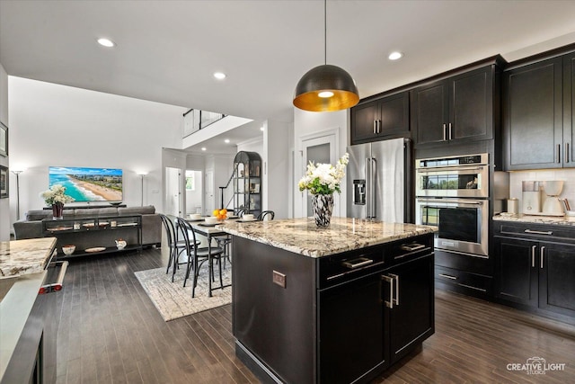 3578 Doral Dr, Elgin, IL 60124 - kitchen with appliances with stainless steel finishes, open floor plan, a center island, light stone counters, and dark wood-style floors