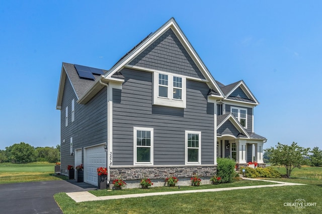 3578 Doral Dr, Elgin, IL 60124 - view of front of house featuring roof mounted solar panels, a front lawn, driveway, an attached garage, and stone siding