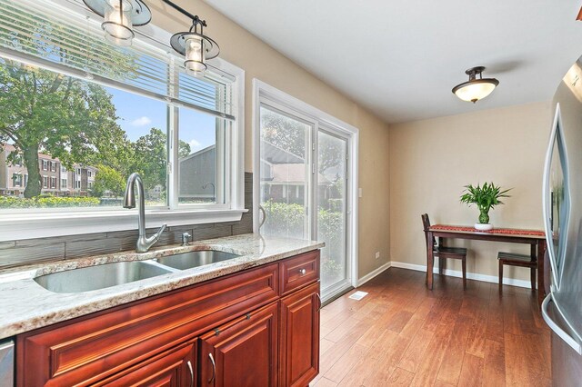 2165 Greystone Pl, Hoffman Estates, IL 60169 - kitchen featuring freestanding refrigerator, reddish brown cabinets, wood finished floors, and light stone counters