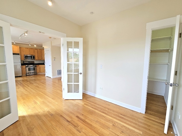 2537.5 Prairie Ave Unit 3N, Evanston, IL 60201 - unfurnished living room featuring french doors, track lighting, and light wood-type flooring