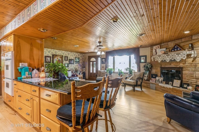 14119 W Maple Rd, Mokena, IL 60448 - kitchen featuring open floor plan, light wood-type flooring, white double oven, wood ceiling, and a stone fireplace