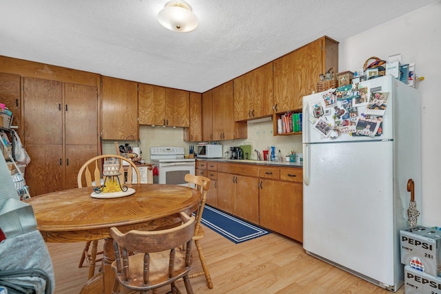 107 N Elm St, Gardner, IL 60424 - kitchen with white appliances, brown cabinets, light wood-style flooring, a textured ceiling, and light countertops