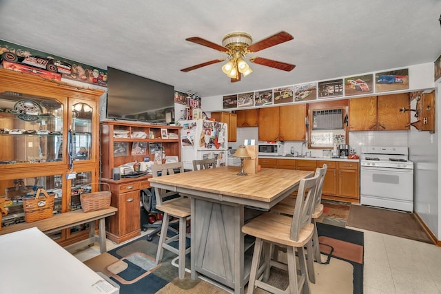 107 N Elm St, Gardner, IL 60424 - kitchen with white appliances, light countertops, a ceiling fan, brown cabinets, and a kitchen breakfast bar