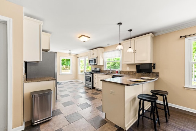 2040 Poplar Ave, Hanover Park, IL 60133 - kitchen featuring appliances with stainless steel finishes, a peninsula, a kitchen bar, decorative light fixtures, and dark stone countertops