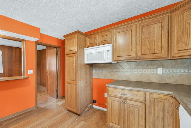319 N Third St, Fisher, IL 61843 - kitchen with white appliances, light wood finished floors, backsplash, brown cabinetry, and a textured ceiling