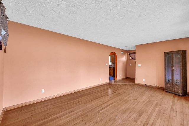319 N Third St, Fisher, IL 61843 - empty room featuring arched walkways, a textured ceiling, and light wood finished floors