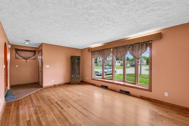 319 N Third St, Fisher, IL 61843 - unfurnished living room featuring light wood finished floors, arched walkways, and a textured ceiling