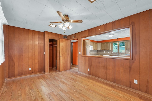 319 N Third St, Fisher, IL 61843 - unfurnished living room featuring light wood finished floors, wood walls, and ceiling fan