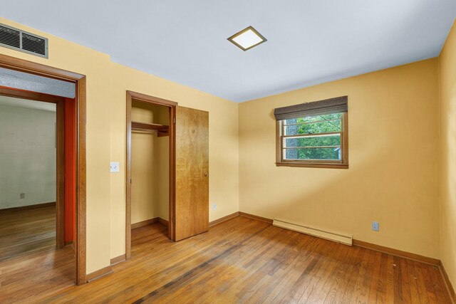 319 N Third St, Fisher, IL 61843 - unfurnished bedroom with baseboard heating, hardwood / wood-style floors, and a closet
