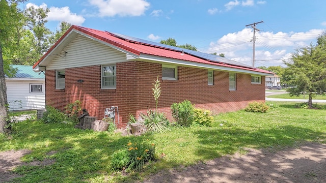 319 N Third St, Fisher, IL 61843 - view of property exterior with roof mounted solar panels, brick siding, a lawn, and a metal roof