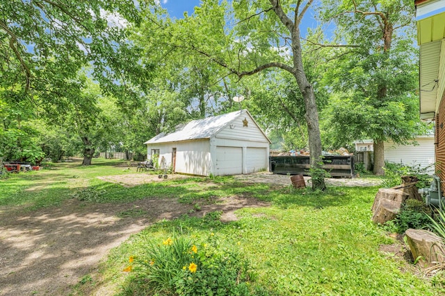 319 N Third St, Fisher, IL 61843 - view of grassy yard featuring a detached garage, an outdoor structure, and view of scattered trees