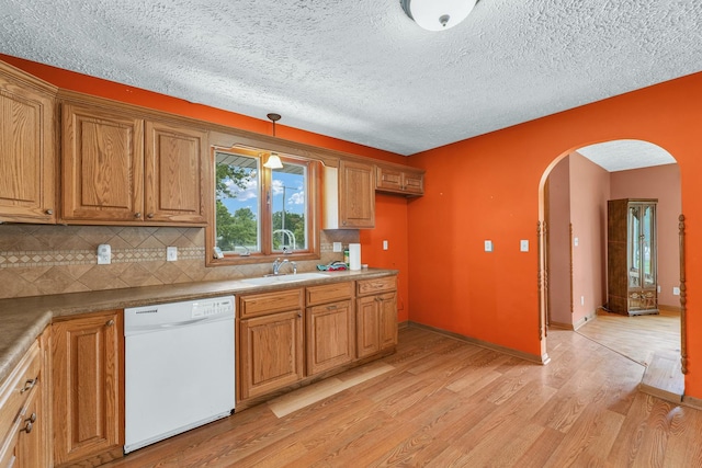 319 N Third St, Fisher, IL 61843 - kitchen featuring white dishwasher, arched walkways, light wood-style floors, brown cabinets, and tasteful backsplash