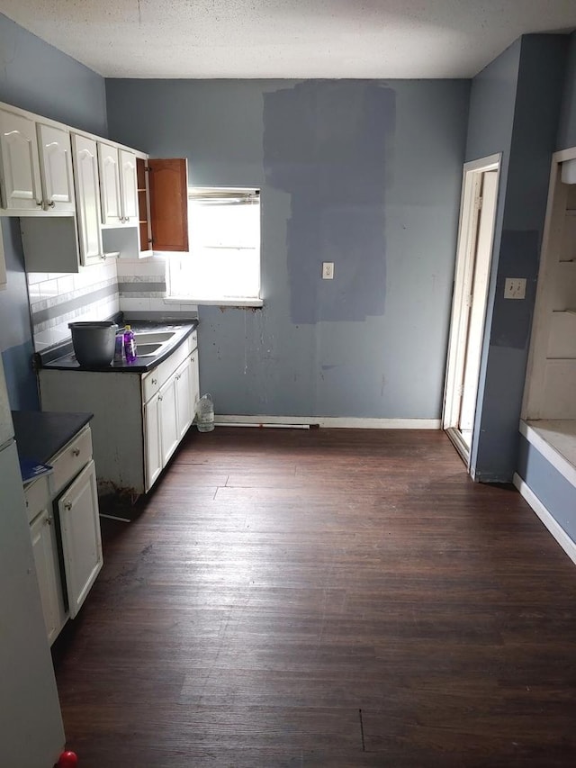 kitchen featuring dark wood-style flooring, white cabinetry, and vaulted ceiling