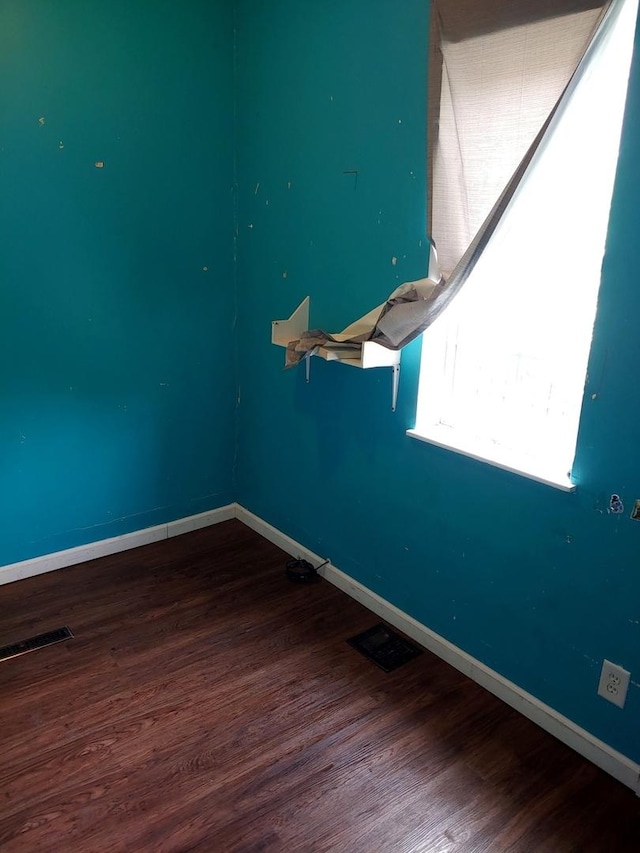 spare room with baseboards and wood finished floors