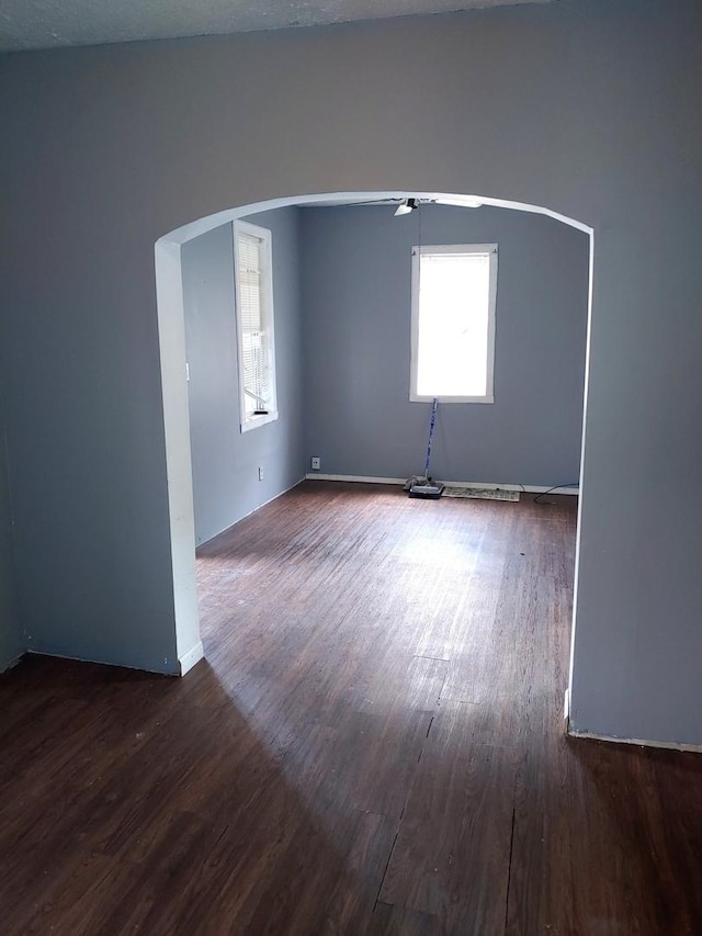 empty room featuring wood finished floors and arched walkways