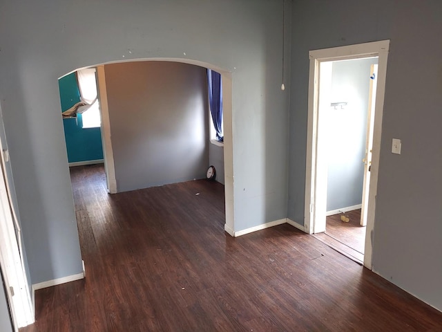 unfurnished room with wood finished floors and arched walkways