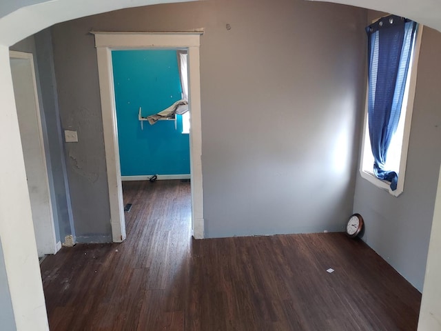 empty room featuring wood finished floors and arched walkways