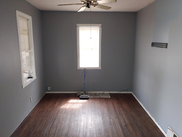 empty room featuring ceiling fan, wood finished floors, and plenty of natural light