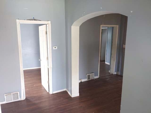 hall featuring arched walkways and wood finished floors