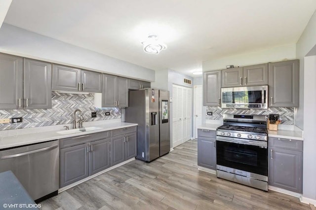 3521 Park Pl, Flossmoor, IL 60422 - kitchen with stainless steel appliances, gray cabinetry, decorative backsplash, and light wood-style floors