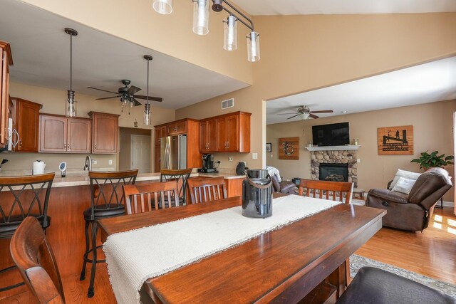 236 Marquette Pl S, Manteno, IL 60950 - dining room featuring a ceiling fan, a stone fireplace, wood finished floors, and a towering ceiling