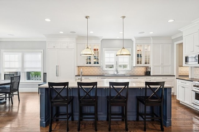 924 Linden Ave, Wilmette, IL 60091 - kitchen with stainless steel microwave, backsplash, white cabinetry, an island with sink, and dark wood-type flooring