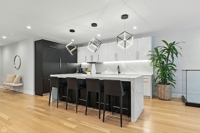 1437 W Grand Ave Unit 1S, Chicago, IL 60642 - kitchen featuring modern cabinets, a center island, light wood-style floors, light countertops, and a breakfast bar