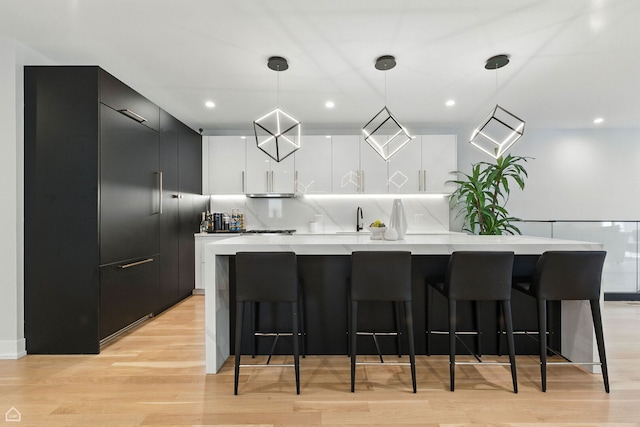 1437 W Grand Ave Unit 1S, Chicago, IL 60642 - kitchen with modern cabinets, a large island, light countertops, a breakfast bar area, and hanging light fixtures