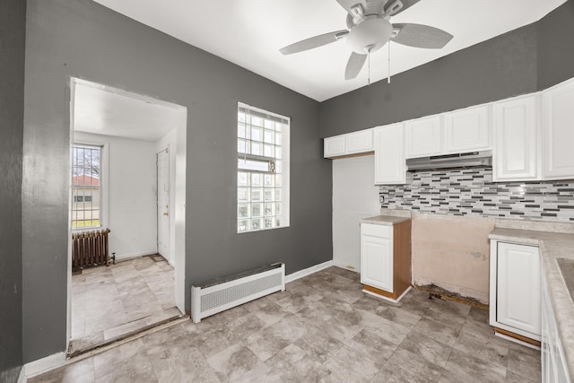 7647 S Calumet Ave, Chicago, IL 60619 - kitchen featuring radiator, under cabinet range hood, white cabinets, tasteful backsplash, and a ceiling fan