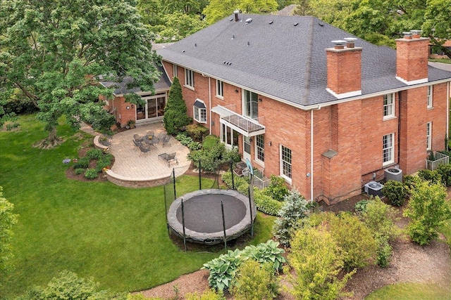 67 Brandon Rd, Northfield, IL 60093 - rear view of property featuring a trampoline, a patio, a lawn, and a chimney