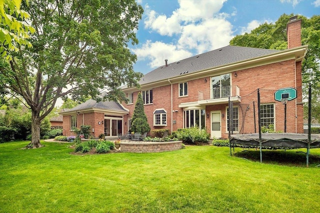 67 Brandon Rd, Northfield, IL 60093 - back of property with a trampoline, a chimney, a lawn, and brick siding